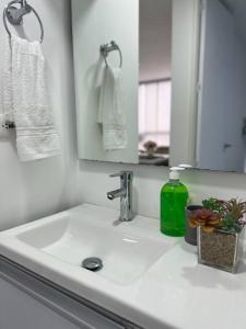 a bathroom sink with a mirror and a green bottle of soap at Espacio acogedor en Piedecuesta, Santander. in Piedecuesta