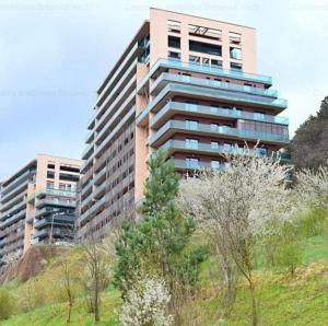 a tall building on a hill with trees in front of it at Apartament “La Iepure” in Braşov