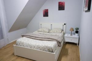Habitación blanca con cama y mesita de noche en Nov Sweety Home en Goussainville