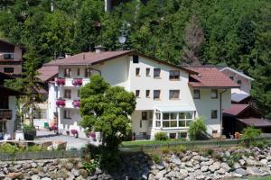 a large white house sitting next to a river at Hotel Garni Dias in Kappl