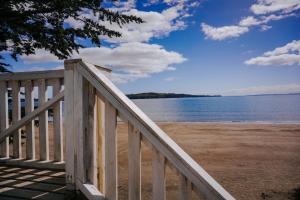 a wooden staircase leading to a beach with the water at Cabañas Kompatzki in Ancud