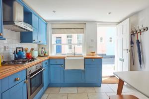 una cocina con armarios azules y fregadero en The Boat House en Aldeburgh