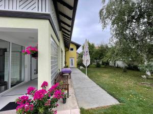 een veranda van een huis met roze bloemen en een paraplu bij Oaza in Jelah