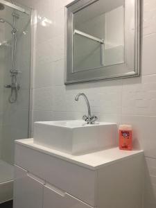 ein weißes Badezimmer mit einem Waschbecken und einem Spiegel in der Unterkunft Chambres du Domaine Spa-piscine sauna in Lescout