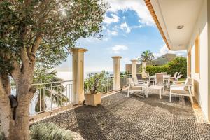einen Balkon mit einem Tisch, Stühlen und Meerblick in der Unterkunft Capela - Casa das Neves in Funchal