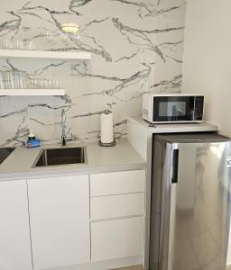 a white kitchen with a microwave and a refrigerator at KASA Seaview at Coral Beach - Studio for 2 Balcony BEACHFRONT BUILDING POOL in San Juan