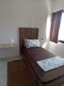 1 dormitorio con 1 cama con cabecero y ventana en Appartement luxueux à louer à Taounate en Taounate