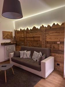a living room with a couch and a wooden wall at Appartamento "Roby" in pieno centro a Cavalese in Cavalese