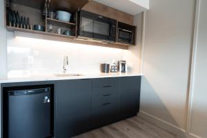 a kitchen with black cabinets and a sink at Hôtel & Suites Normandin Lévis in Lévis