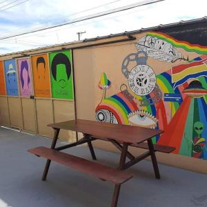 un banc assis devant un mur avec une fresque murale dans l'établissement Hostel Resende, à Resende