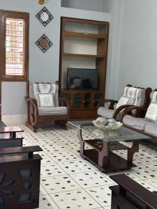 sala de estar con sillas, TV y mesa en Alom Manzil - 4 Bedroom Family Home en Sylhet