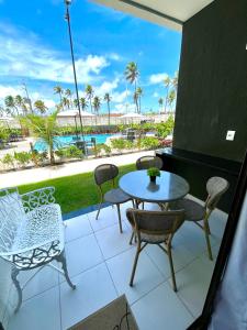 a patio with a table and chairs and a view of the beach at Muro Alto - Flat Completo MANA Resort in Porto De Galinhas