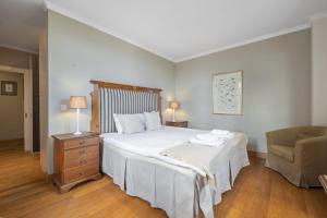 a bedroom with a large white bed and a chair at Vila Botânica in Funchal