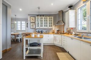 a kitchen with white cabinets and a wooden floor at Vila Botânica in Funchal