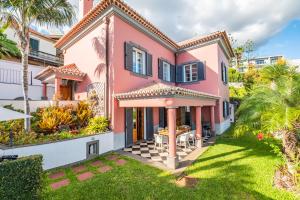 a pink house with a yard at Vila Botânica in Funchal