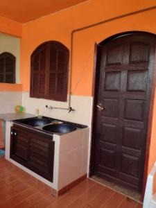 an orange kitchen with a black door and a sink at Conforto e simplicidade! Casa top com garagem, cozinha, banheiro e quarto in Cabo Frio