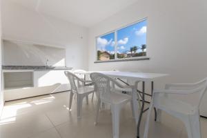a white dining room with a white table and chairs at Beach Townhouses #C13 - Apartamento por Carpediem in Aquiraz