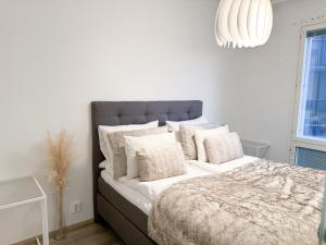 a white bedroom with a large bed with white pillows at Hostit Arctic Apartments in Rovaniemi