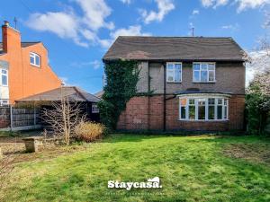 a brick house with a grass yard in front of it at Detached King Suite With Large Garden & Driveway in Leicester