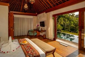 um quarto com uma cama e uma grande janela em Nau Villa Ubud em Tegalalang