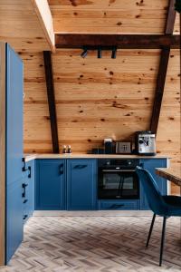 una cucina con armadi blu e una parete in legno di KARL's Cabin by Black & White Panoramic a Rimetea