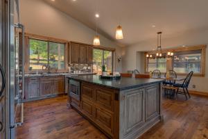 a large kitchen with wooden cabinets and a large island at Spruce Haven by Tahoe Getaways at Tahoe Donner - Luxury Pet Friendly Cabin w Private Hot Tub in Truckee