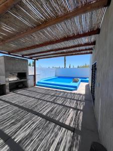 an outdoor deck with a swimming pool and a wooden ceiling at Casa con pileta privada in General Alvear