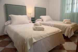 una camera con due letti con lenzuola e asciugamani bianchi di Casa Centro Fuengirola a Fuengirola