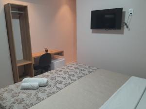 a bedroom with a bed with a television and a desk at LC Palace Hotel in Capim Grosso
