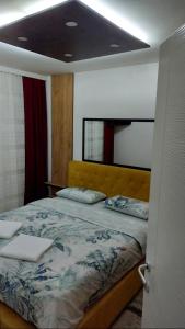a bedroom with a bed with a yellow headboard at Apartman Luna in Valjevo