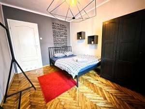 a small bedroom with a bed and a red rug at Apartament Vincent in Toruń