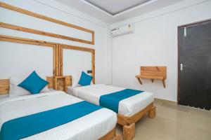 two beds in a room with a window and a door at Hotel Greencity Comforts in Bangalore