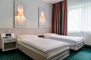 a hotel room with two beds and a window at Hotel Falkenhagen in Pritzwalk