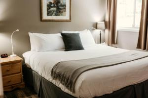 una camera da letto con un grande letto con lenzuola e cuscini bianchi di Page's Inn on Silva Bay a Gabriola