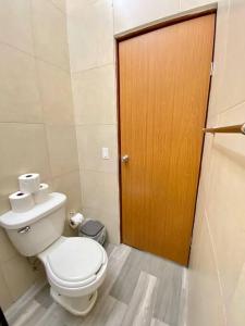 a bathroom with a toilet and a wooden door at Casa para vacacionar in Cabo San Lucas