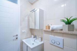 La salle de bains blanche est pourvue d'un lavabo et d'un miroir. dans l'établissement Rooms&Apartments Tomić, à Ston