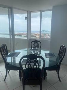 a glass table and chairs with a view of the ocean at Hermoso Apartamento con una de las mejores vistas in Panama City