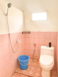 baño con aseo y cubo azul en Homestay Kamar Tamu Selomartani 3, en Sleman
