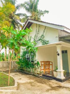 una piccola casa bianca con un portico e un albero di Homestay Kamar Tamu Selomartani 3 a Sleman