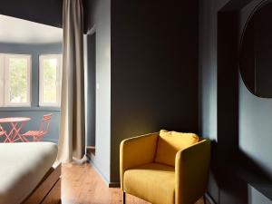 a bedroom with a yellow chair and a table at Avenue Hostel & Suites in Lisbon