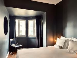 a bedroom with a bed and a chair next to a window at Avenue Hostel & Suites in Lisbon