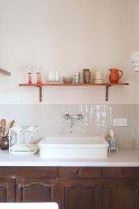 a kitchen with a white sink and shelves on the wall at Appartement cosy sur la route des vins d'Alsace in Dambach-la-Ville