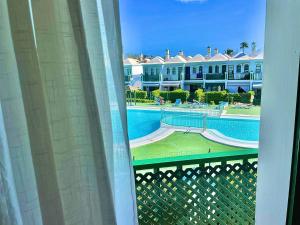 uitzicht op een zwembad vanuit een raam van een resort bij Bungalow Dunaflor Verde 5 by SunHousesCanarias in Maspalomas