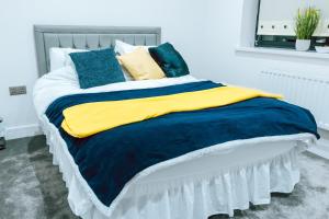 Cama con mantas y almohadas azules y amarillas en Cosy 1Bed Apart with Wifi en Purley