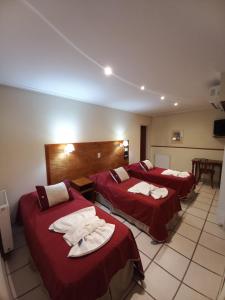 three beds in a hotel room with red sheets at Hotel Francia in Tandil