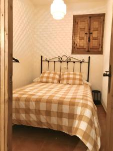 - une chambre avec un lit et une couverture en damier dans l'établissement CASA VALLE VERDE, à Lentegí