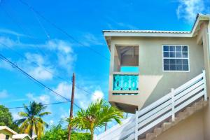 a house with a blue sky and palm trees at Cozy Modern Upstairs 2 Bed A/C Apt Near 2 Everything in Saint Philip