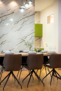 a dining room table with chairs and a marble wall at Unique Apartments in Prishtinë