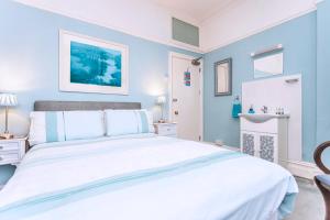 Dormitorio azul con cama blanca y lavamanos en The Ravensbourne Hotel, en Bournemouth
