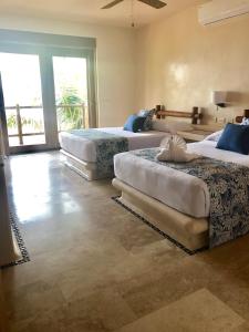 a bedroom with three beds and a large window at New Beachfront Villa in Playa Blanca in Zihuatanejo